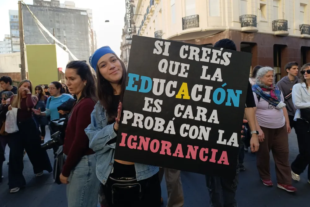 Una joven sostiene un cartel en defensa de la educación pública 